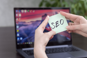 Person holding a sticky note that says "SEO" in front of a laptop (how to update a website)
