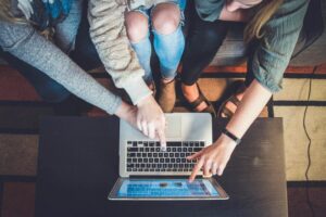 Three people pointing at a laptop with a lead generation website pulled up.