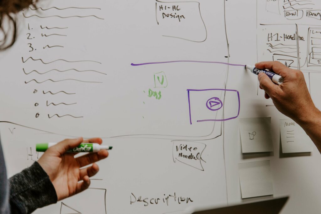 Two marketers at a marker board drawing out a comprehensive growth marketing strategy