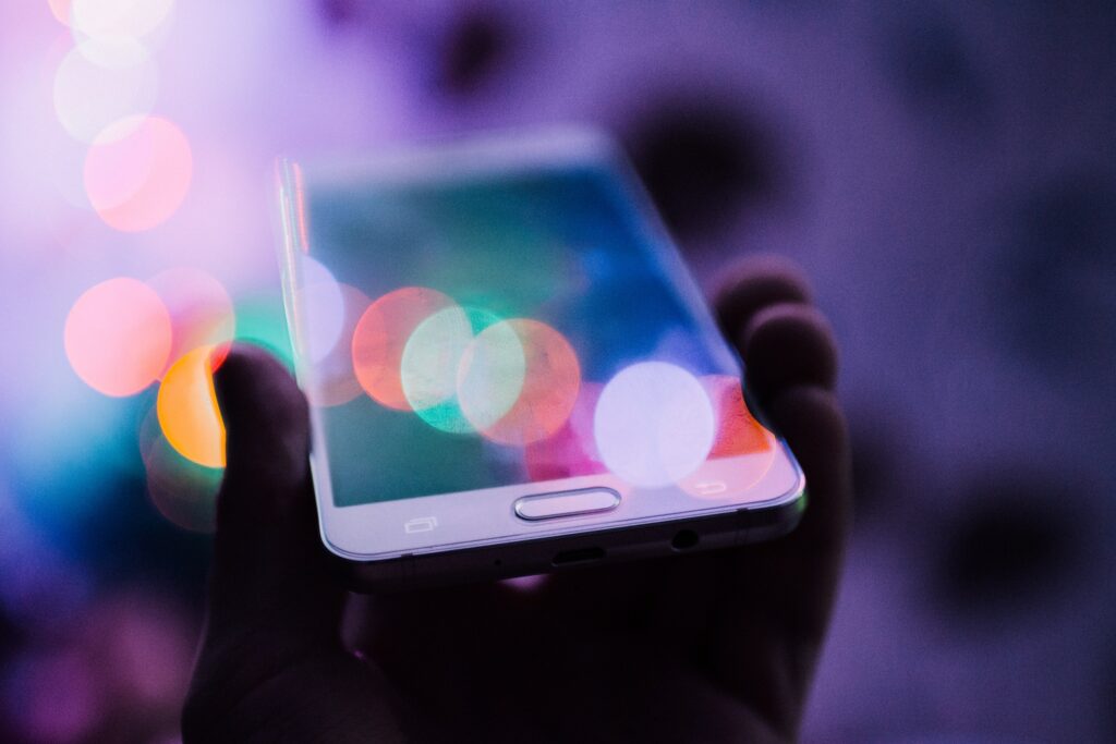hand holding a cell phone against a purple background (voice search)
