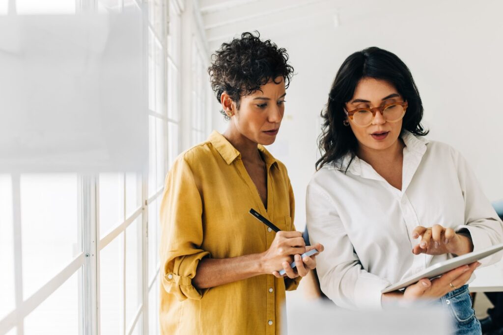Two women looking at and discussing marketing data on a tablet