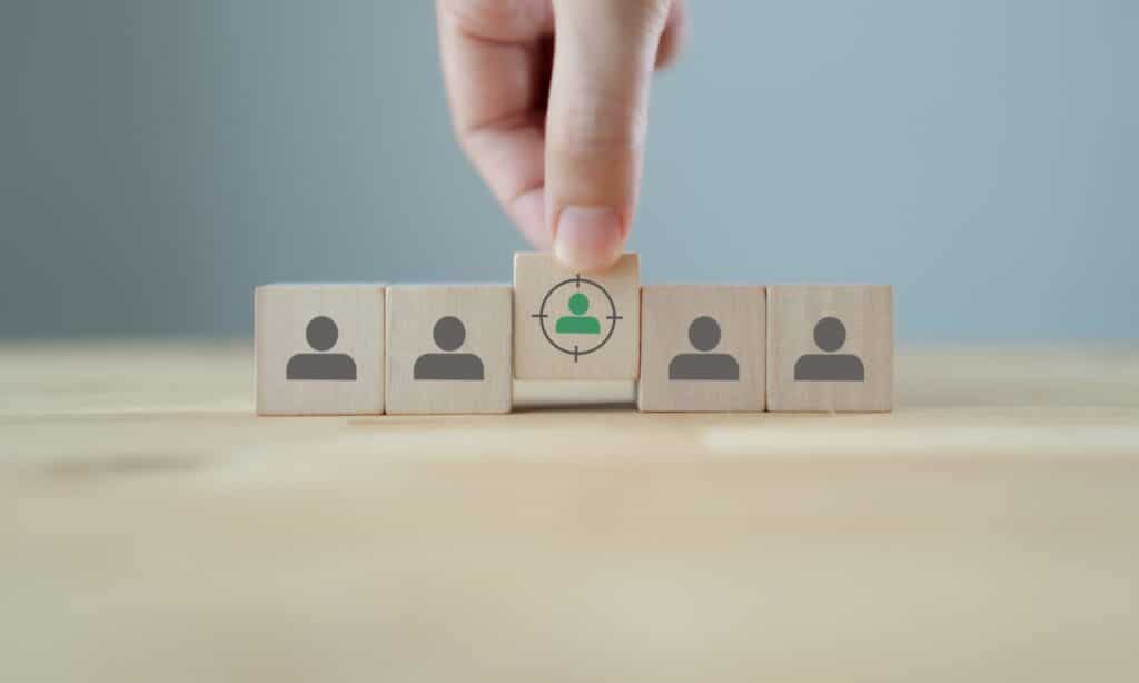 Hand lining up wooden blocks with a "user" icon on them