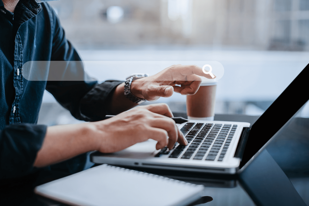 Man typing on laptop with coffee