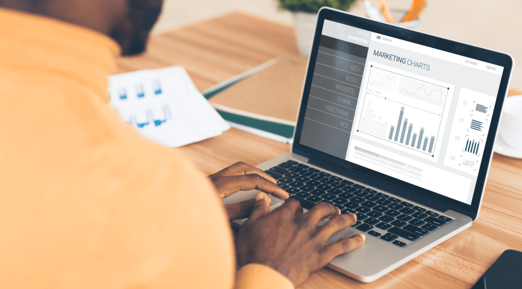 Person typing on a laptop that has marketing analytics on the screen