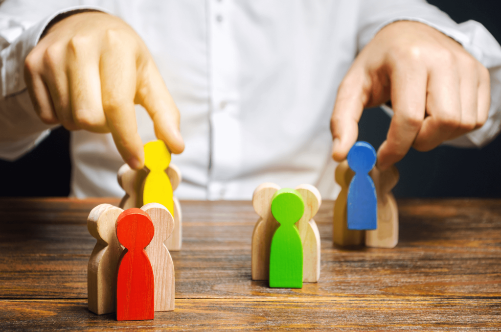 Person using wooden people figurines to demonstrate customer segmentation