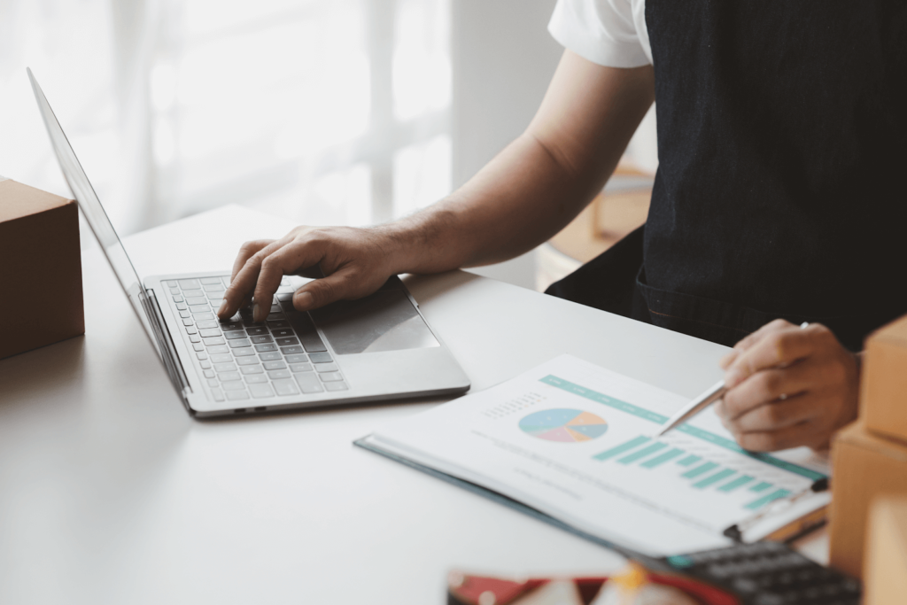 Businessperson with a laptop in one hand and printed marketing analytics in the other