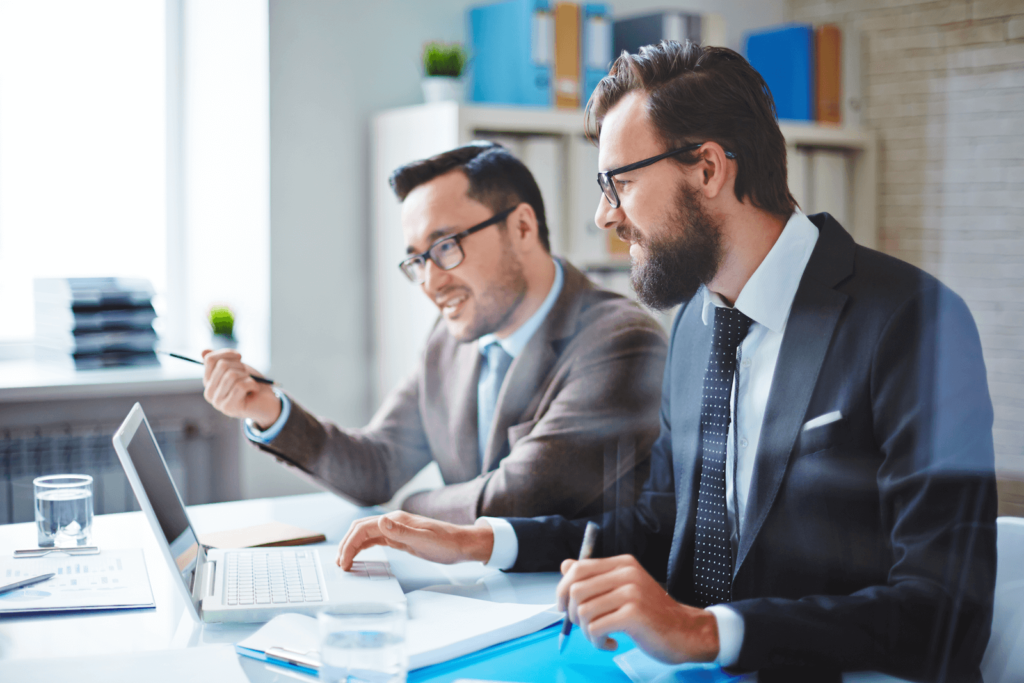 Two marketers at a desk with a laptop discussing their PPC campaign