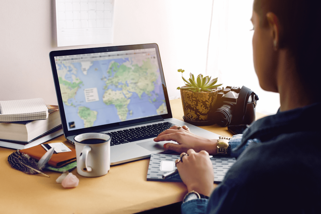Person at a desk with a cup of coffee, a camera, and a laptop displaying a map (local PPC strategy)