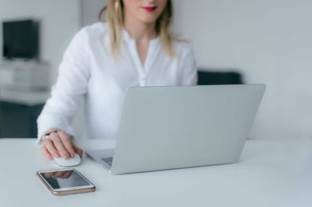 Woman in a white shirt at a desk with her laptop open