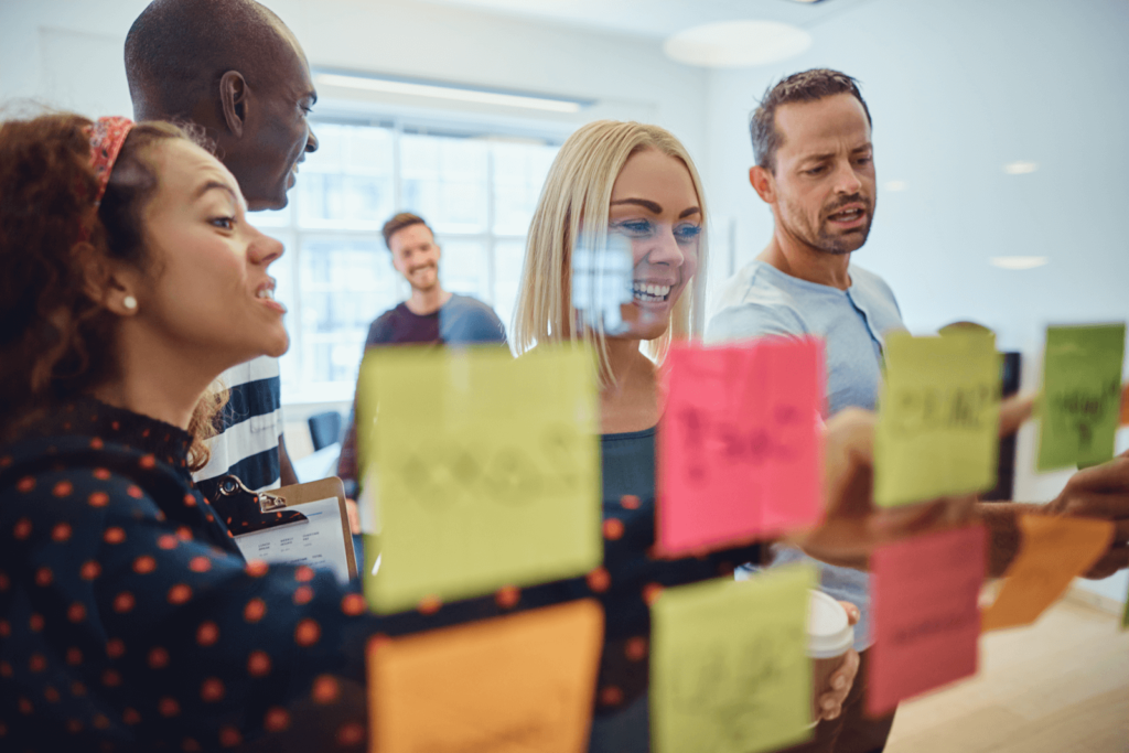 Four marketers at a whiteboard with sticky notes discussing advertising copywriting