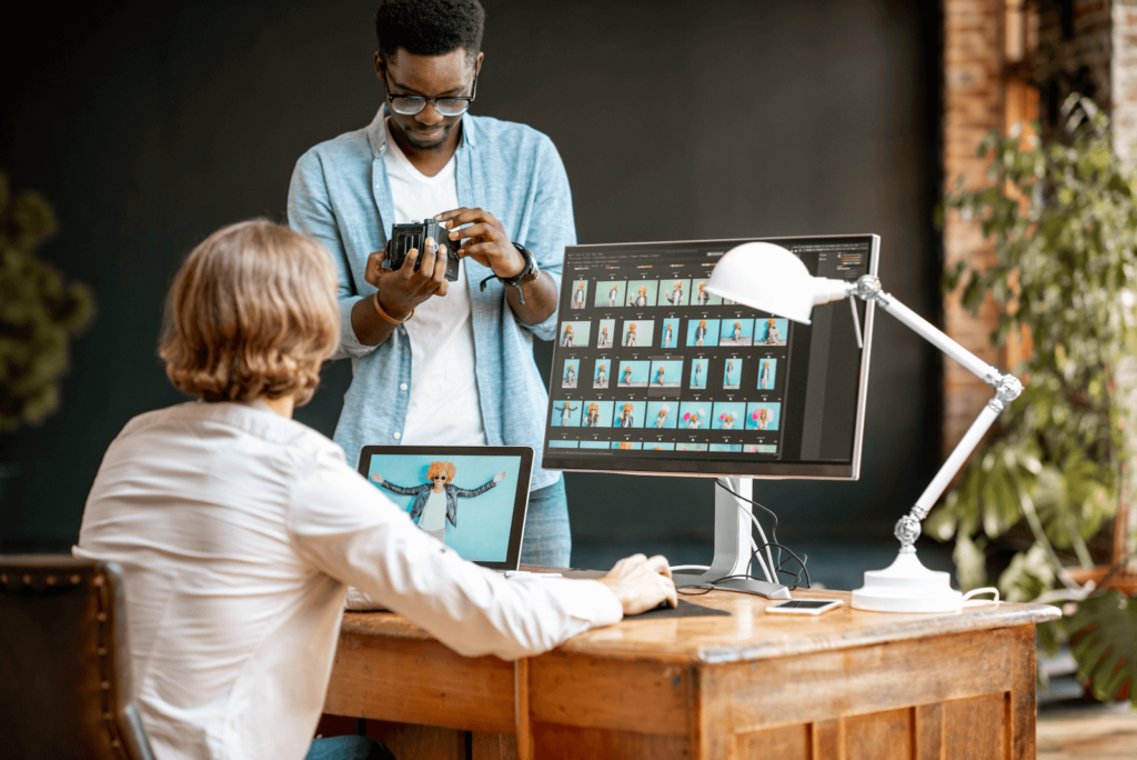 Two marketers at a desk looking at images on a desktop