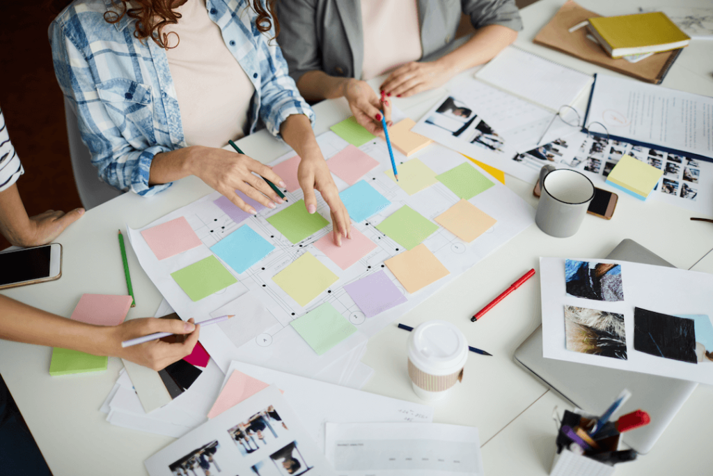 Marketing professionals at a table with sticky notes, papers, and coffee (planning website content)