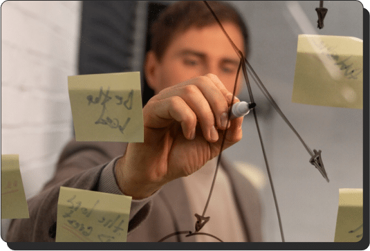 Man pointing to sticky notes on a marker board (marketing consultants)