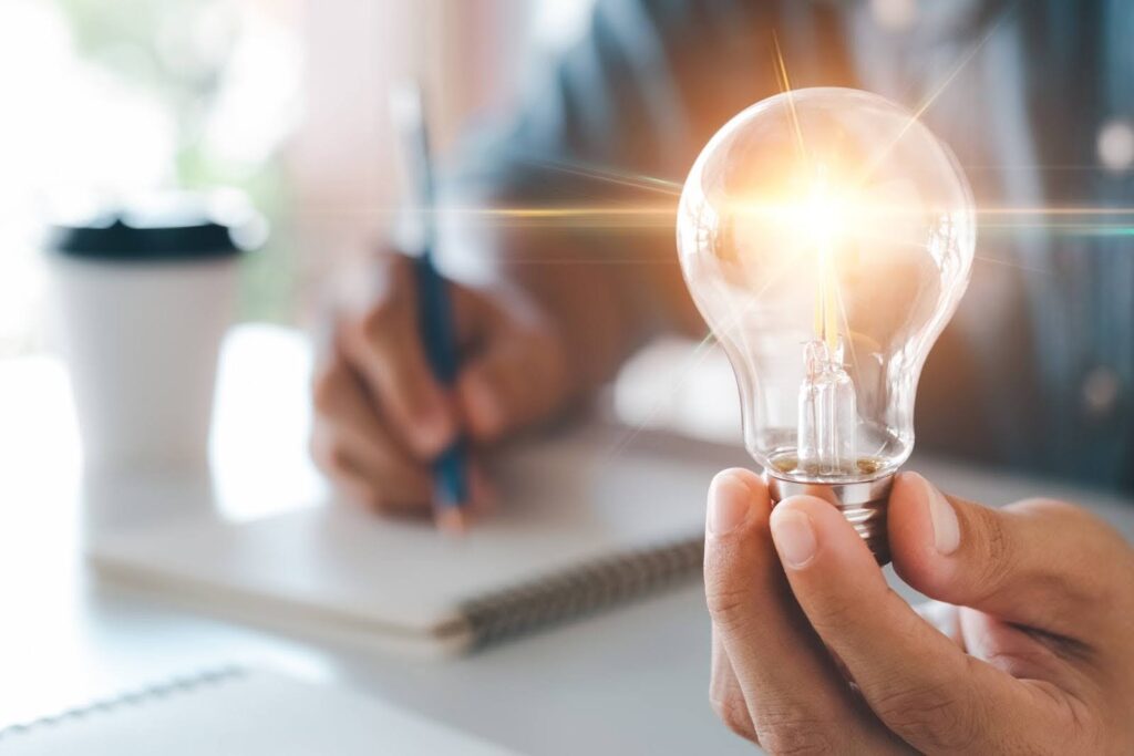 Marketing consultant holding a lightbulb and writing in a notebook