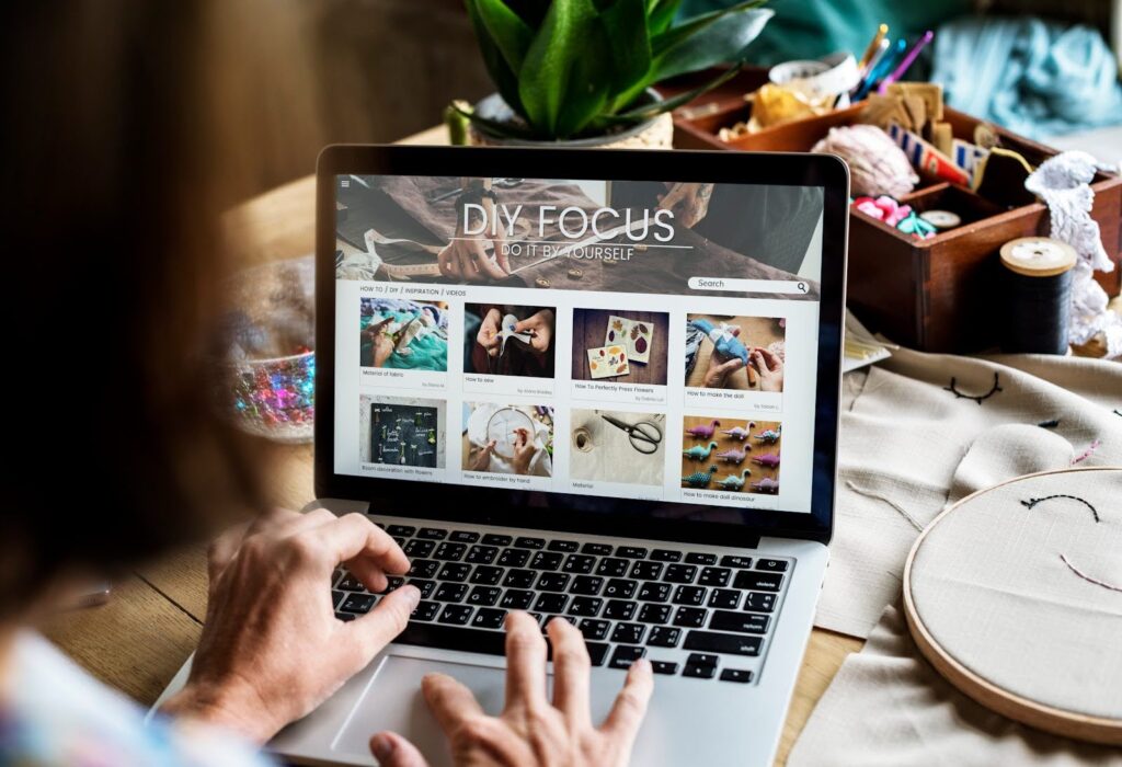 A person is testing page speed on a laptop displaying a website called "DIY Focus," featuring articles about crafting. The background includes craft supplies, plants, and embroidery projects.